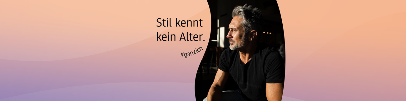 Person mit grauen und schwarzen Haaren in schwarzem T-Shirt sitzt im Schatten vor einem pastellfarbenen Hintergrund mit dem Text ‚Stil kennt kein Alter. #ganzich