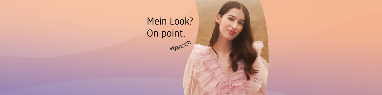 Frau mit langen braunen Haaren und rosafarbenem, gerafftem Kleid steht vor unscharfem Naturhintergrund mit dem Text ‚Mein Look? On point. #ganzich auf pastellfarbenem Hintergrund